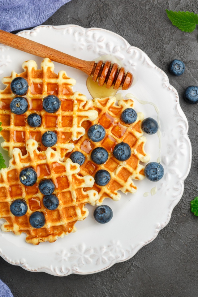 Сладкие вафли с медом на тарелке с ягодами черники