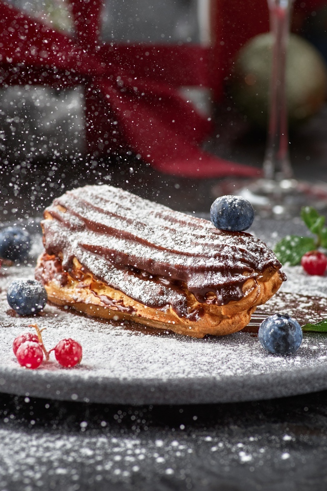 Вкусное пирожное на тарелке с сахарной пудрой и ягодами