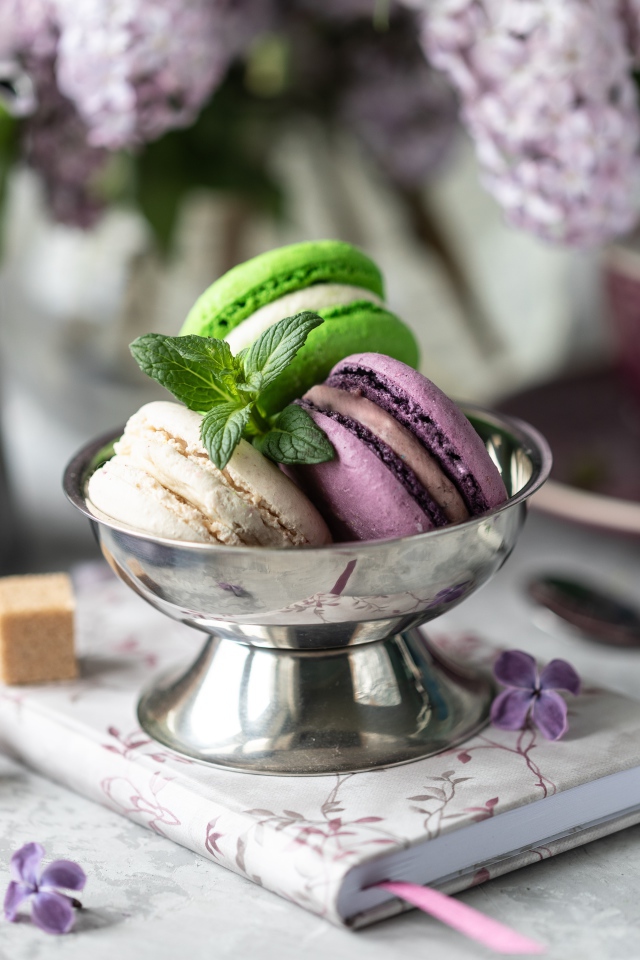 Три печенья макарун на столе с блокнотом