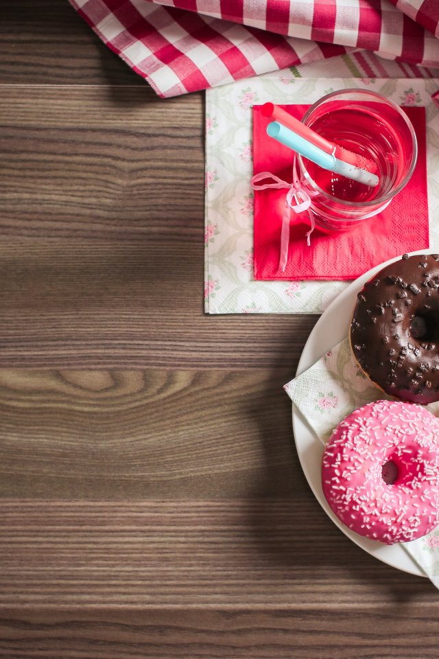 Три сладких пончика с глазурью на столе с лимонадом