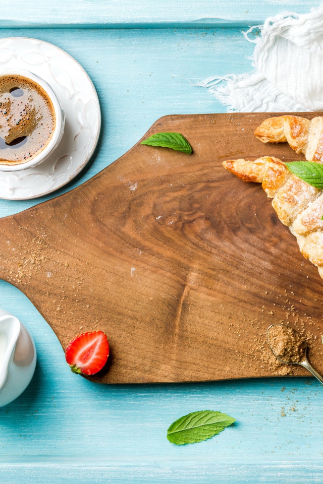 Деревянная доска на столе с круассанами и чашкой кофе