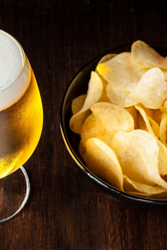 Миска с чипсами на столе с бокалом пива 