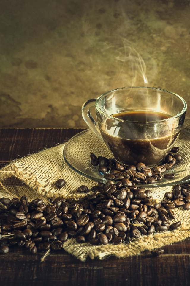 Чашка горячего крепкого кофе на столе с зернами