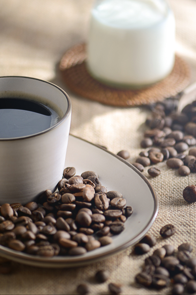 Чашка крепкого кофе на столе с зернами