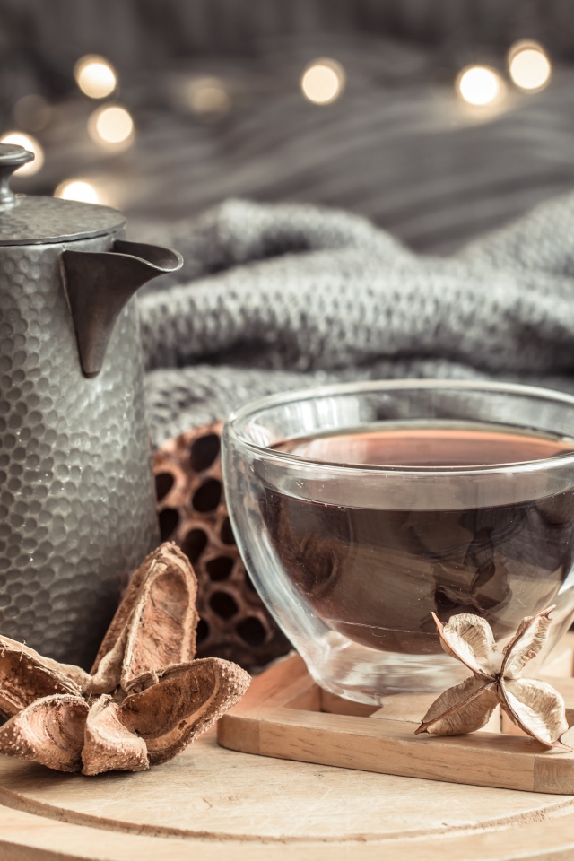 Чашка чая на столе с чайником и теплым пледом