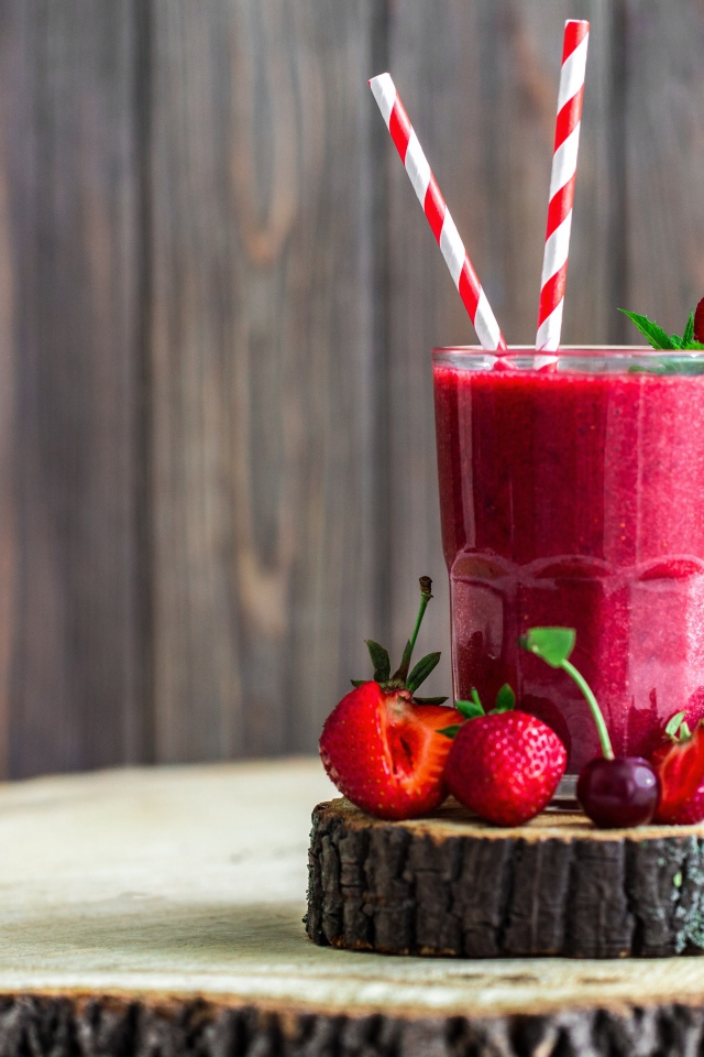 Стакан ягодного смузи на столе с клубникой и вишней