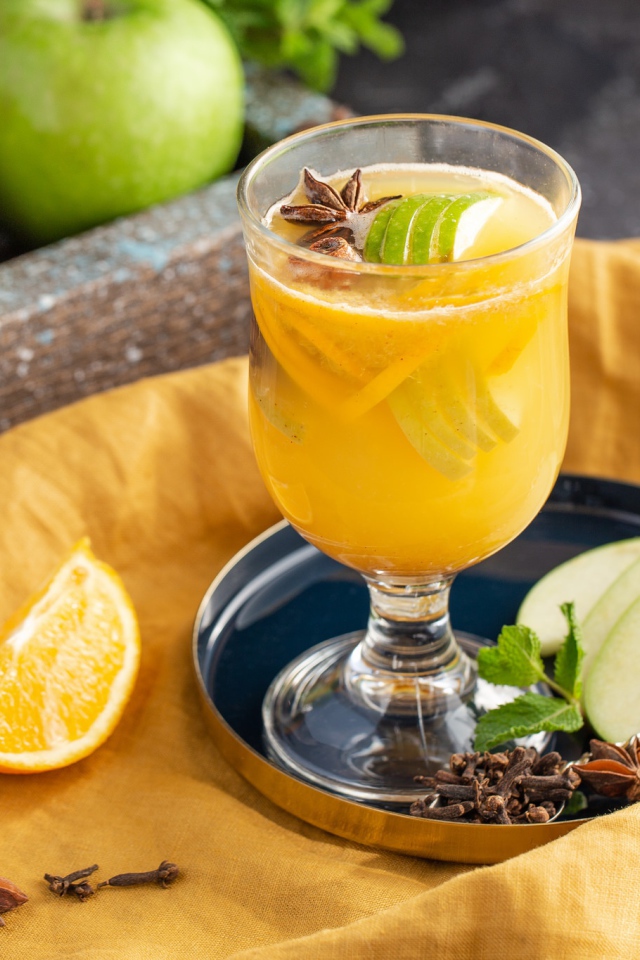 Стакан лимонада на столе с яблоками и корицей 