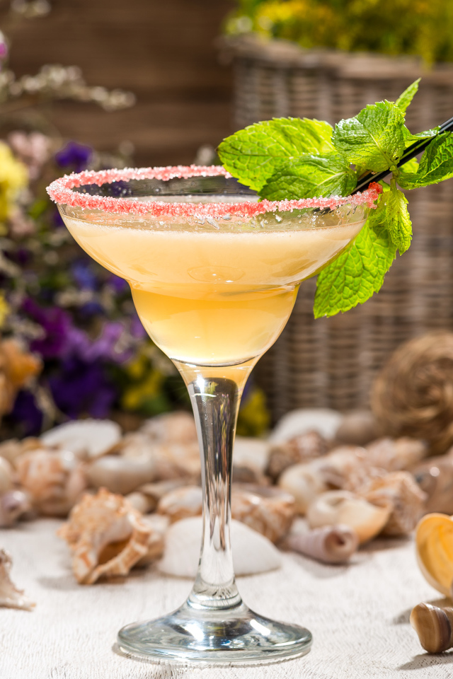 Коктейль с мятой в бокале на столе с ракушками 