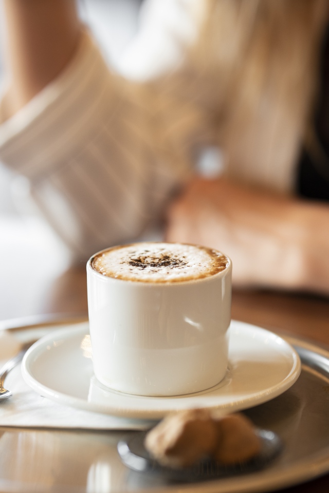 Чашка капучино с корицей на столе в кафе