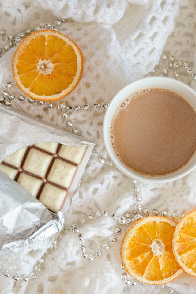 Чашка какао, шоколад и апельсин на белом пледе