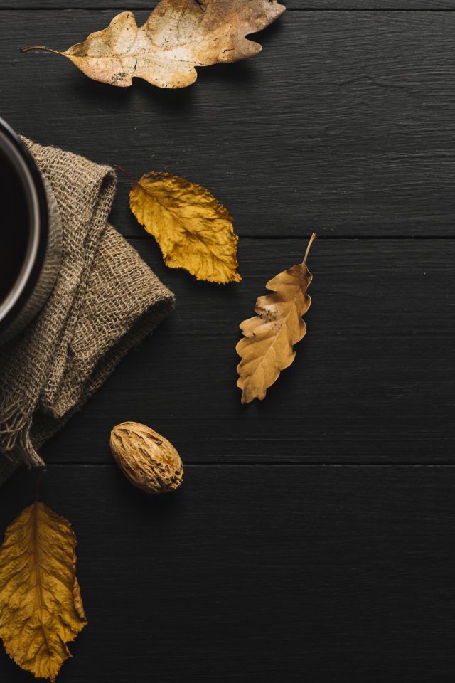 Чашка кофе на черном столе с листьями