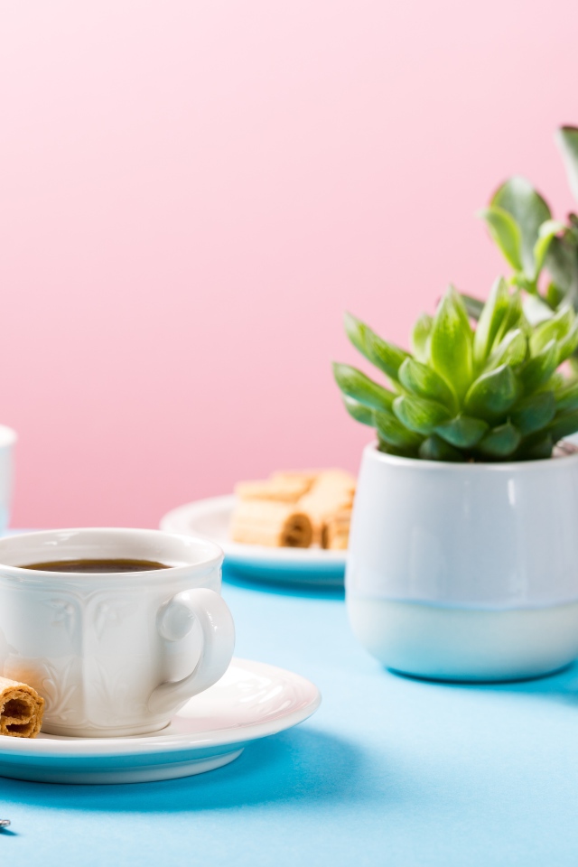 Чашка кофе на блюдце с вафлями на столе с цветами