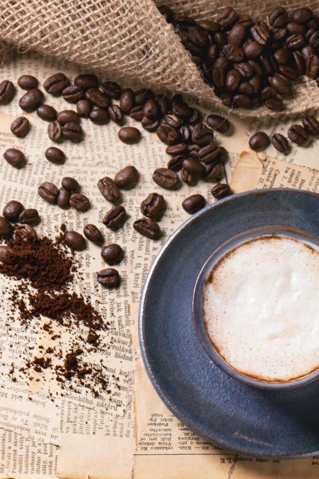 Чашка кофе на столе со старыми газетами и зернами