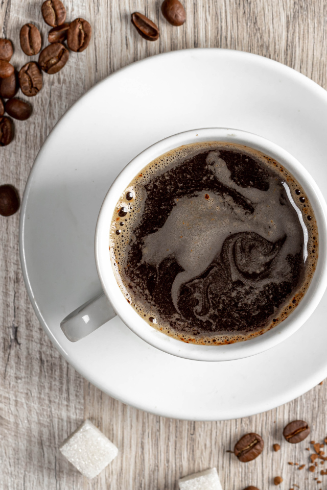 Чашка кофе на столе с сахаром и кофейными зернами