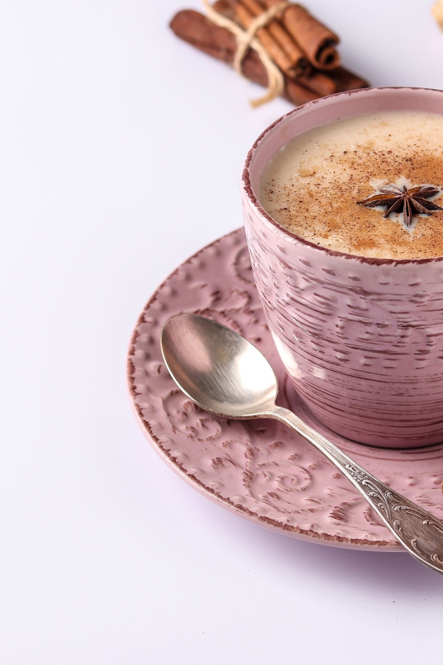 Чашка кофе на столе с корицей, бадьяном и  имбирем на белом фоне 