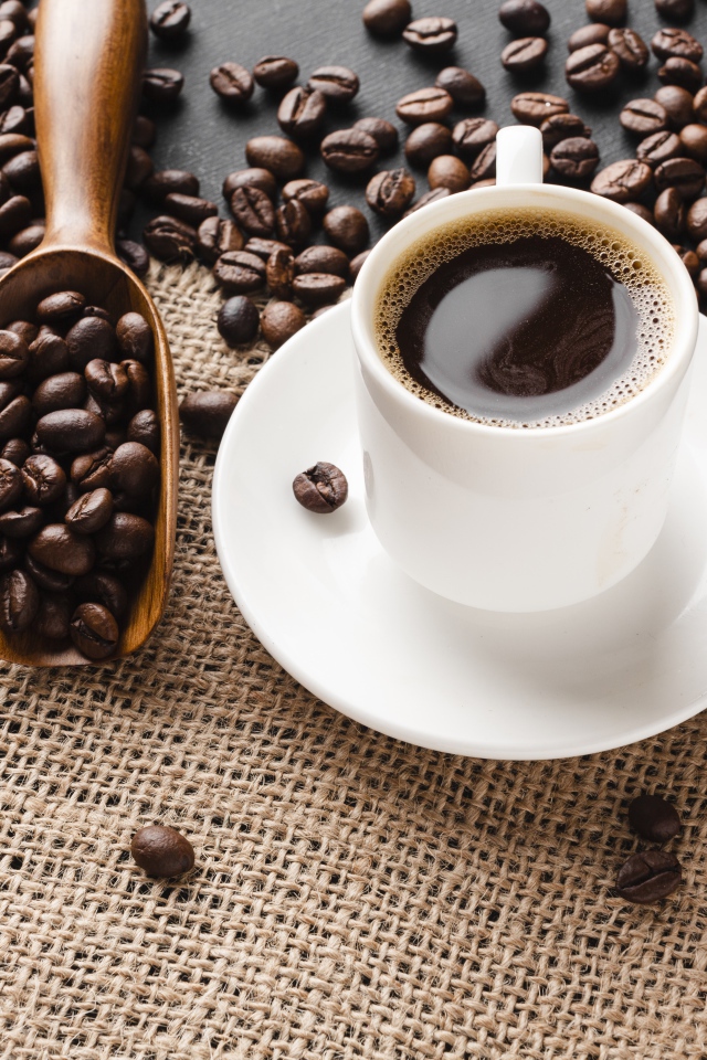 Чашка кофе на столе с зернами 