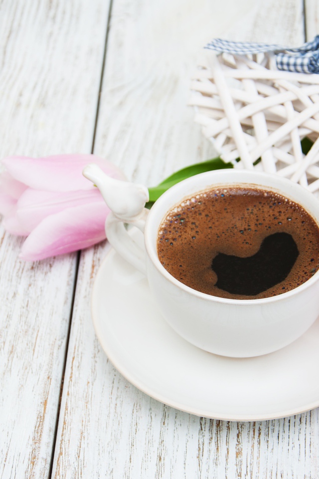 Чашка кофе на столе с розовыми тюльпанами и плетеным сердцем