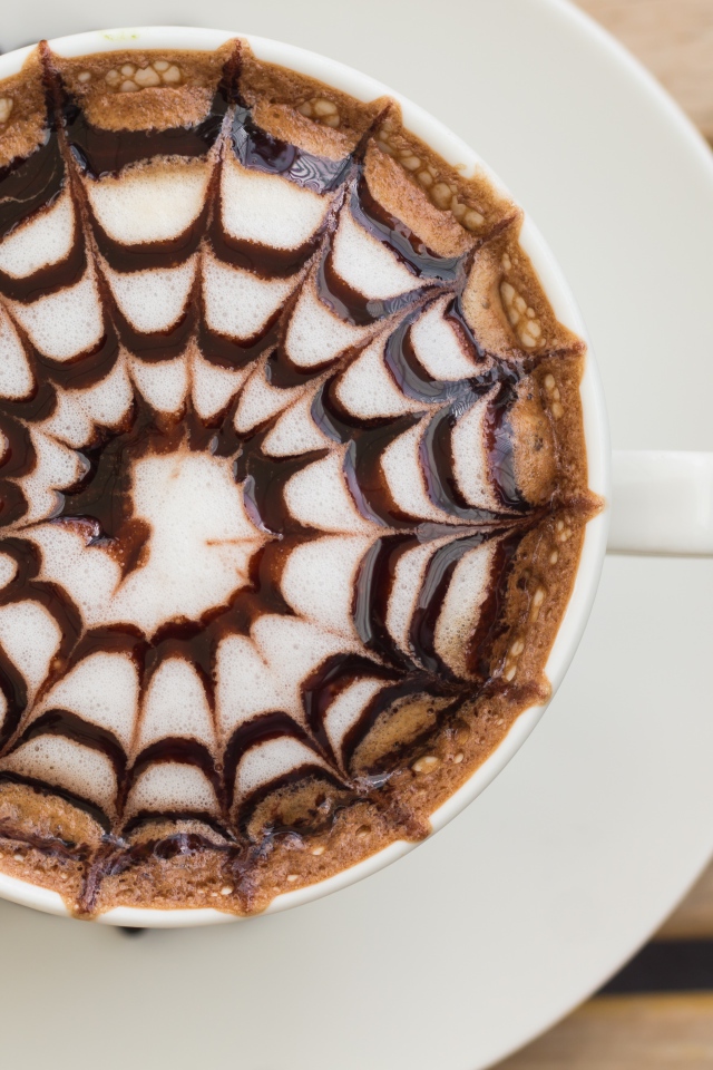 Чашка кофе с рисунком на пене на столе