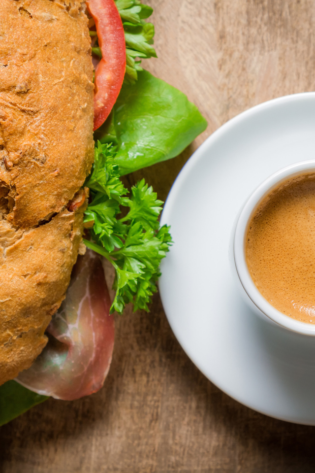 Чашка кофе с бутербродом на столе к завтраку 