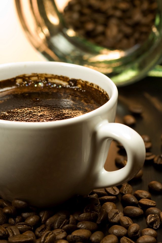 Чашка горячего кофе на столе с зернами