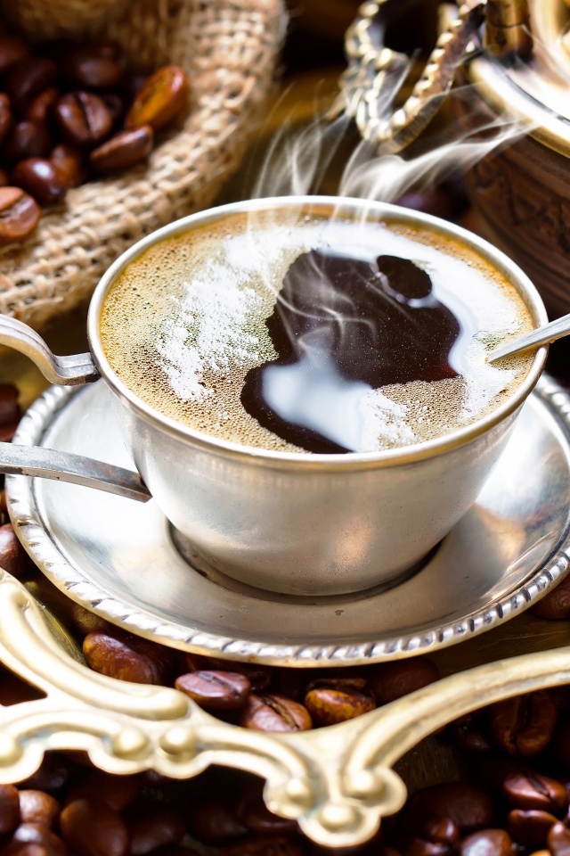 Чашка горячего вкусного кофе на столе с зернами