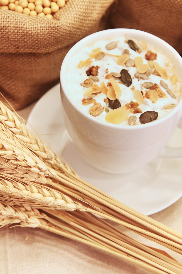 Чашка молока с мюсли на столе с колосками