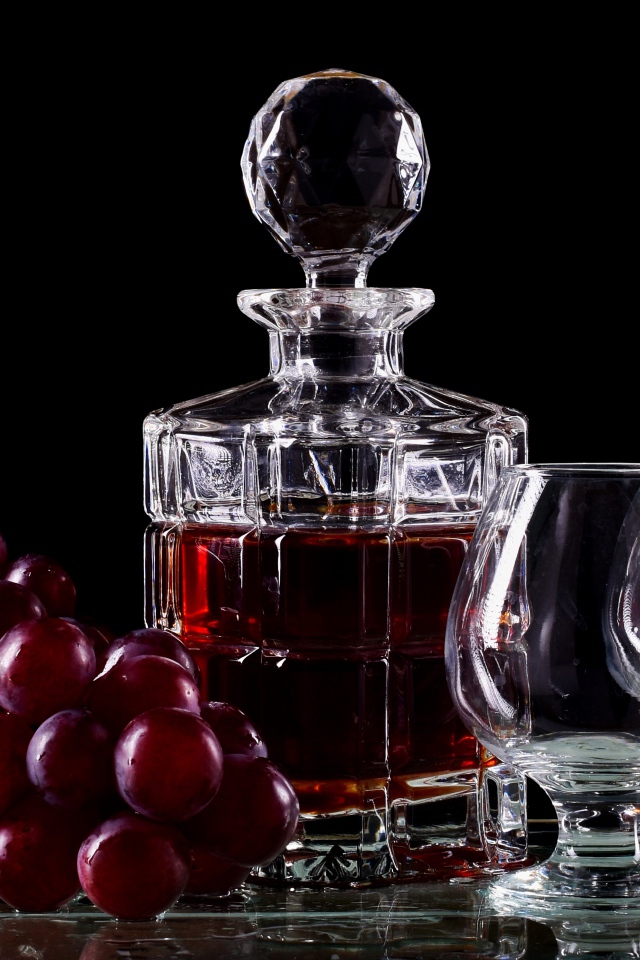 Графин с коньяком на столе с бокалами и виноградом