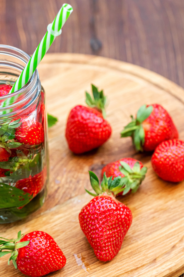 Напиток  в банке с ягодами клубники и трубочкой