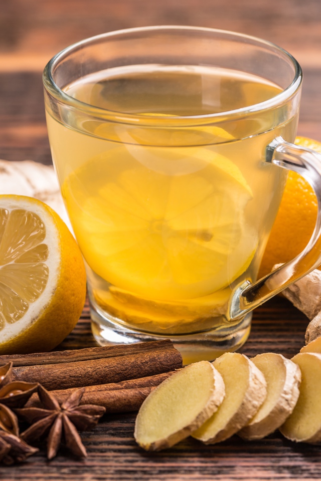 Стеклянная чашка чая на столе с лимоном, имбирем и специями