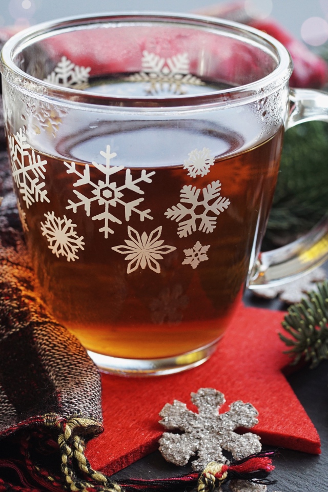 Стеклянная чашка чая на столе с ветками ели и шарфом 