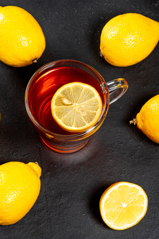 Стеклянная чашка чая с лимоном на сером столе 