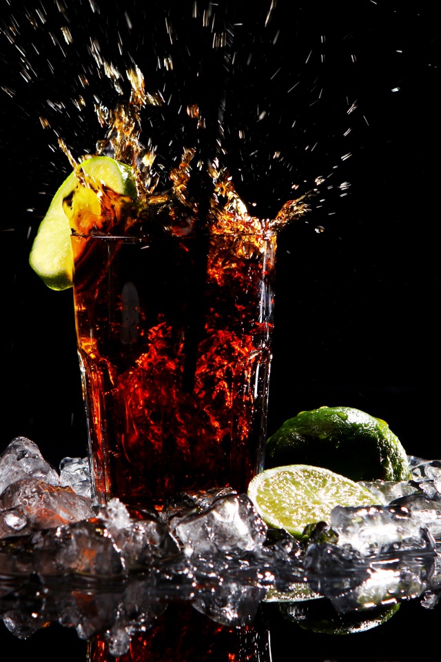 Стакан кока колы на черном фоне со льдом