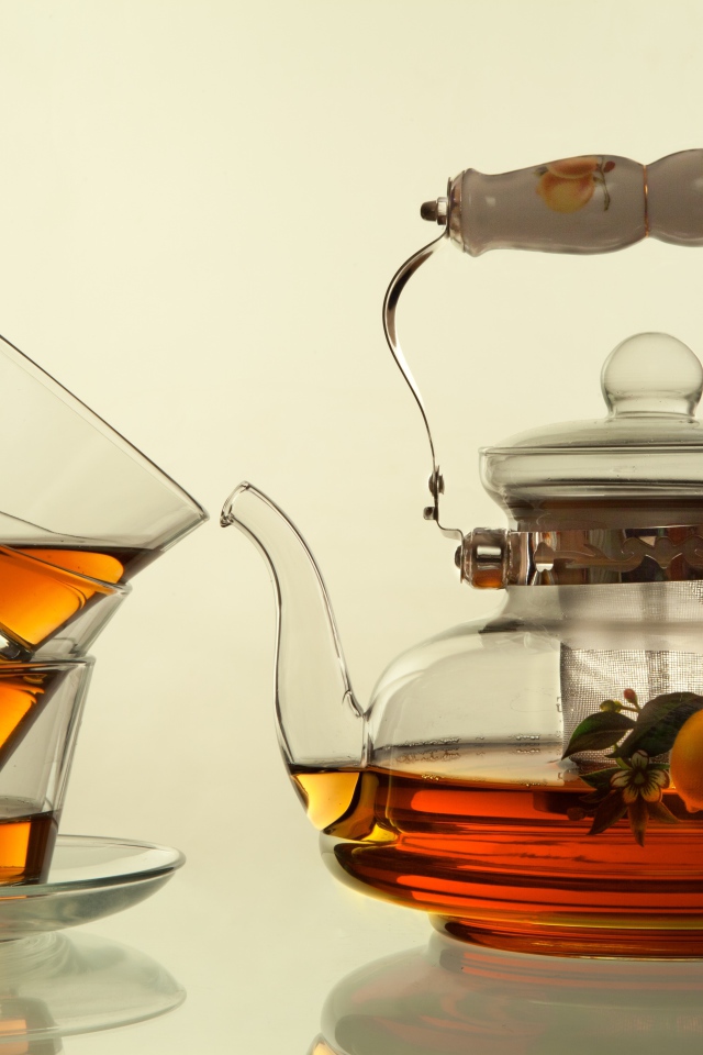 Стеклянный чайник с чашками на белом фоне