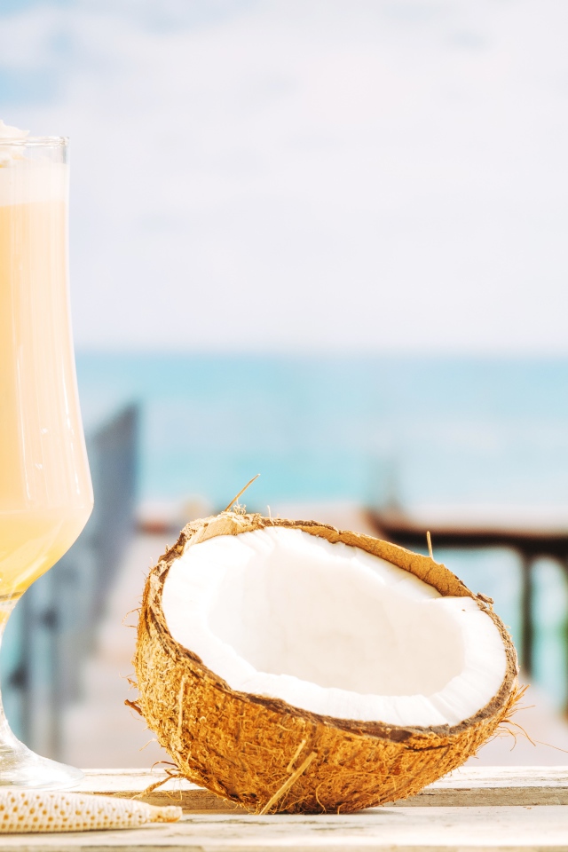 Стакан с коктейлем на столе с кокосом 