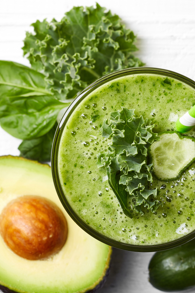 Зеленый смузи на столе с огурцом, авокадо и зеленью