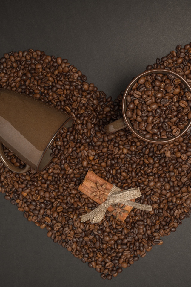 Heart made of coffee beans on a gray background with mugs