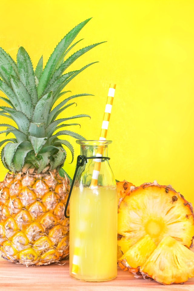 Сок в бутылке на столе с ананасами