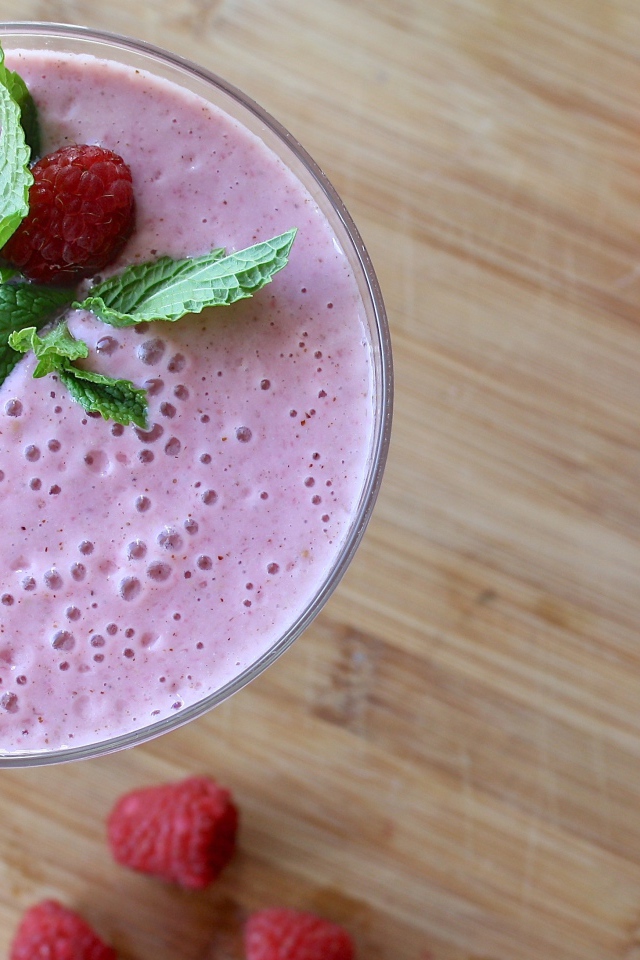 Малиновый смузи в стакане на столе с герберами