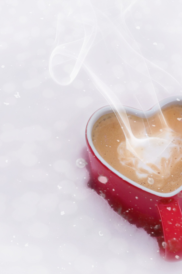 Красная чашка в форме сердца с кофе на снегу