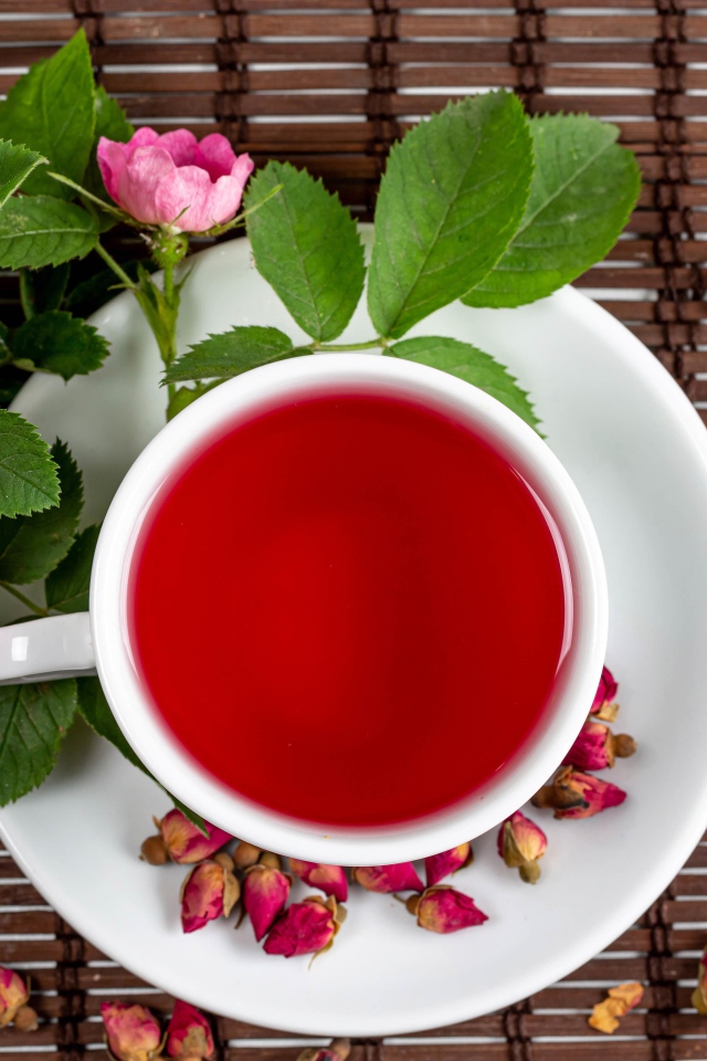 Красный чай с шиповника на столе с цветами