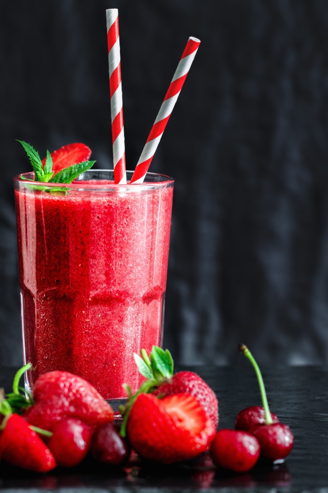 Смузи с ягодами клубники и вишни на столе