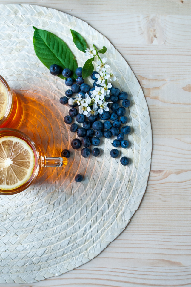 Чай с лимоном на столе с ягодами клубники и черники