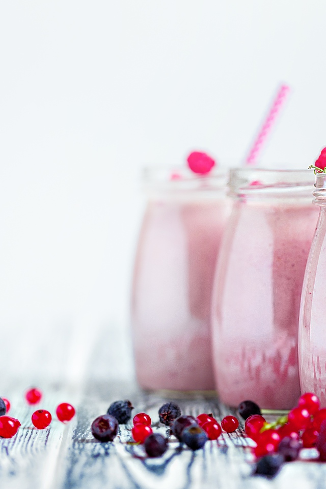 Три банки с ягодным смузи на белом фоне