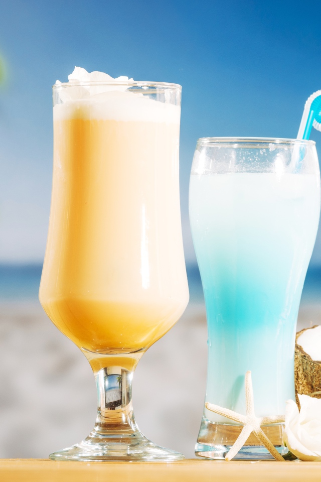 Два коктейля с кокосом на столе на тропическом пляже