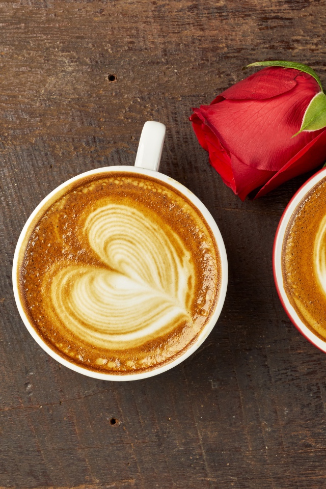 Две чашки капучино на столе с красной розой 
