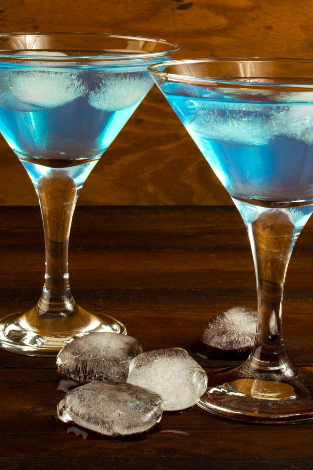 Два бокала коктейля на столе с кусочками льда