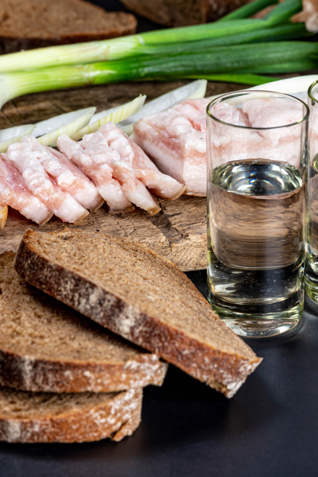 Две рюмки водки на столе с аппетитной закуской 