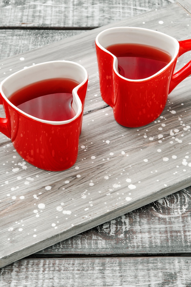 Две красные чашки в форме сердца на столе 