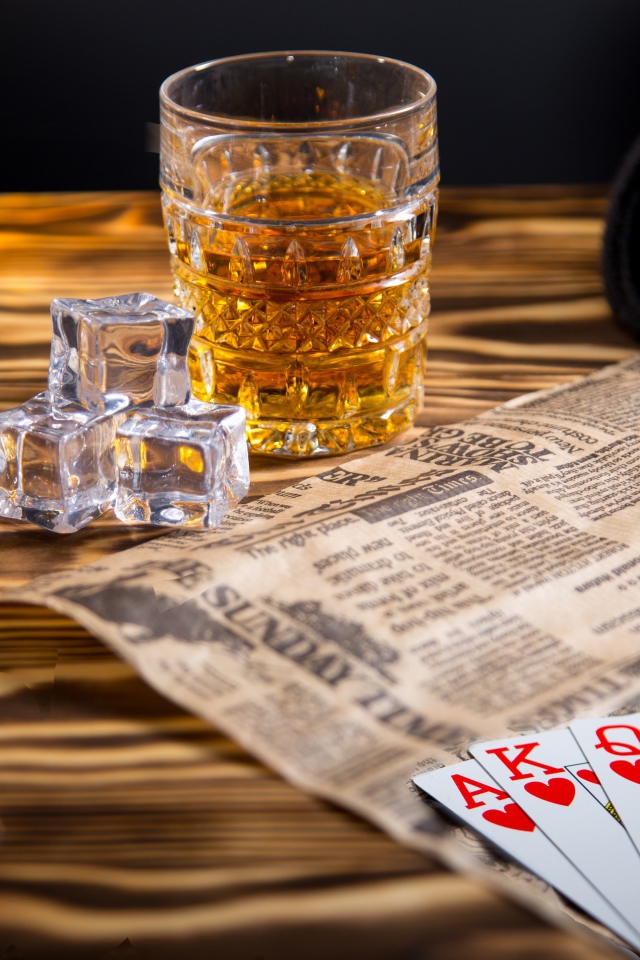 Виски со льдом на столе с картами, газетой и шляпой