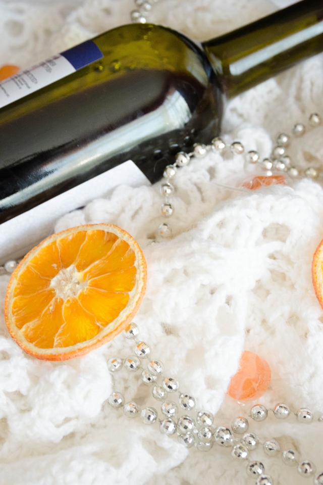 Бутылка вина и кусочки апельсина на белом платке 